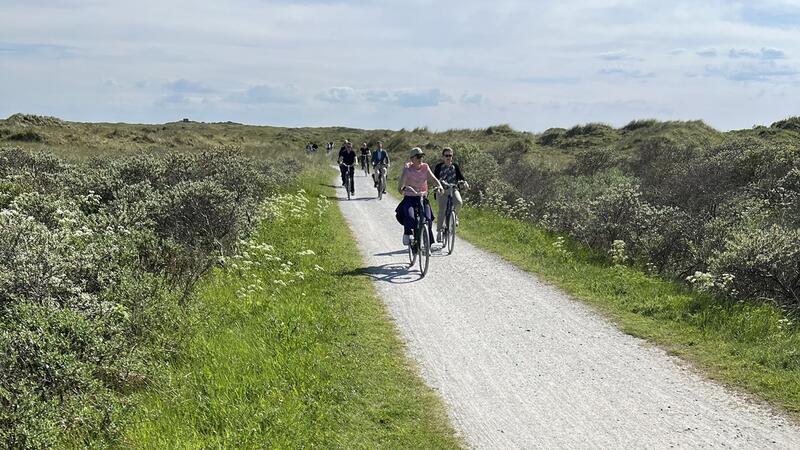 Bicyclists on road between vegetated dunes. CWSS/ Bostelmann.